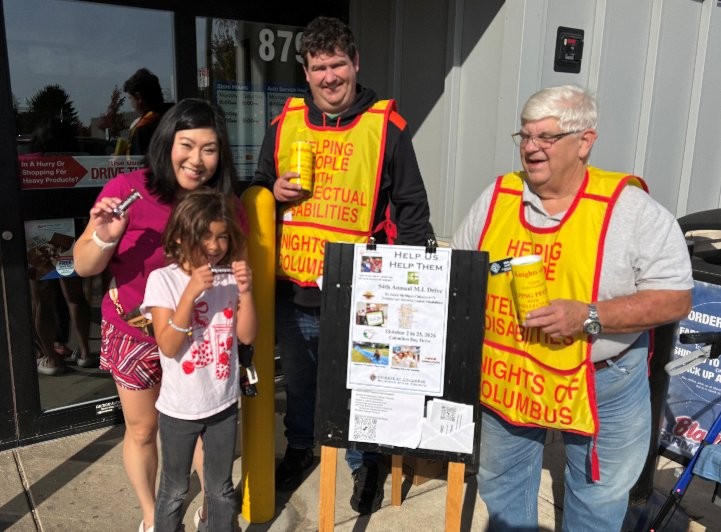 Council 6980 Knights and a volunteer family collecting outside a store during the MI Drive
