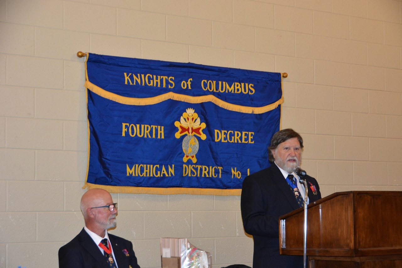 Speaker at the podium beneath the Fourth Degree Michigan District No. 1 banner