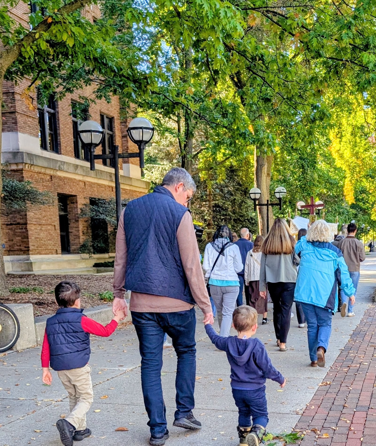 A father and two young sons walking in the Eucharistic Procession