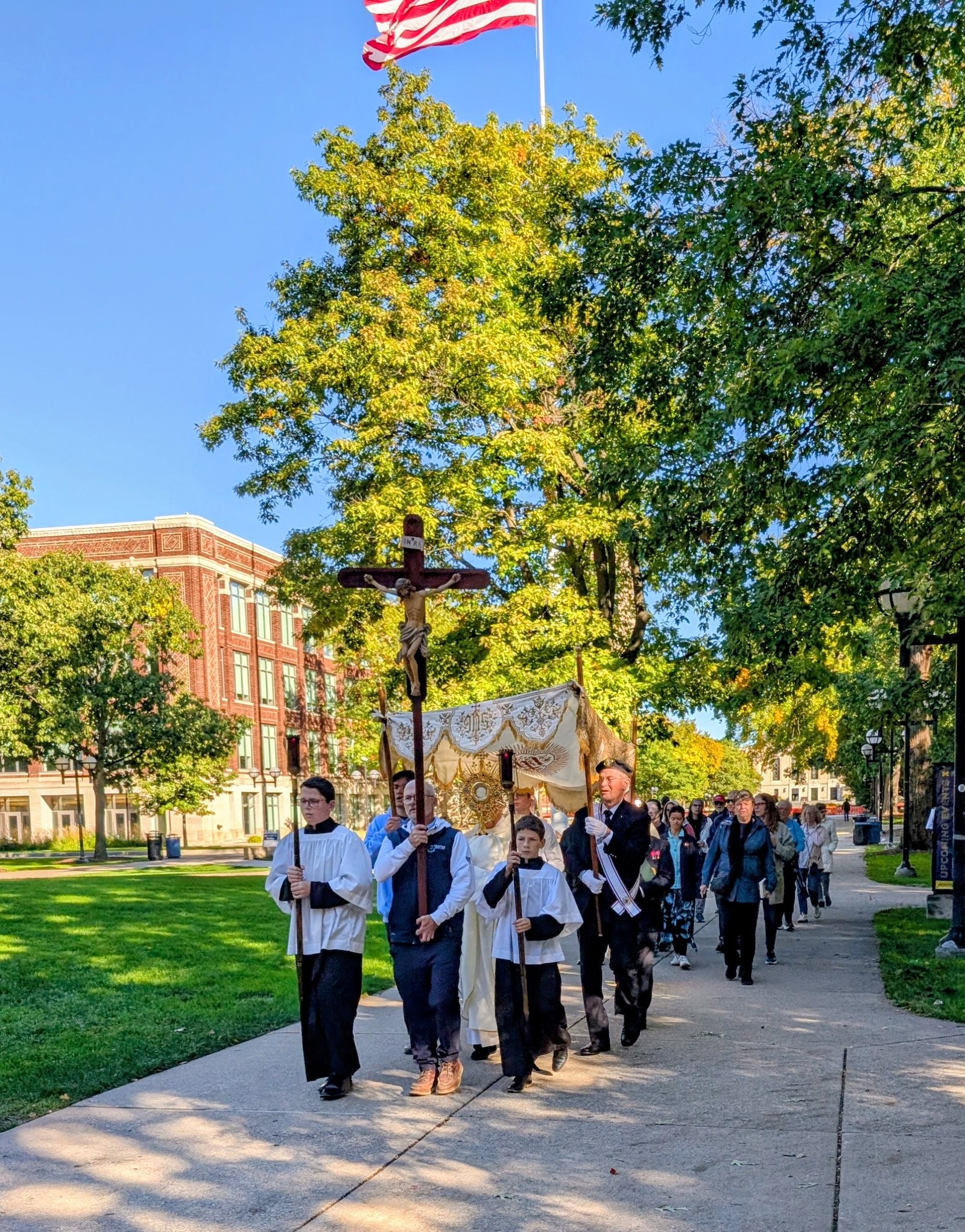 The Eucharistic Procession with crucifix and canopy crossing the Diag