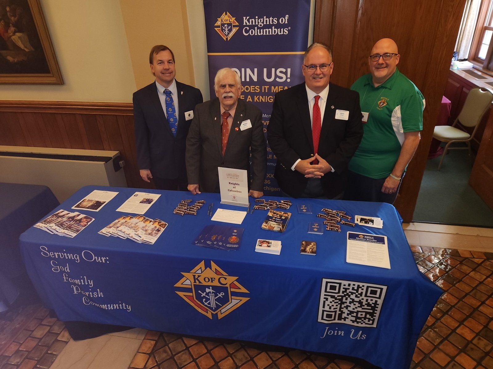 Four Knights of Columbus members standing behind the KofC recruiting table at Sacred Heart Major Seminary in Detroit